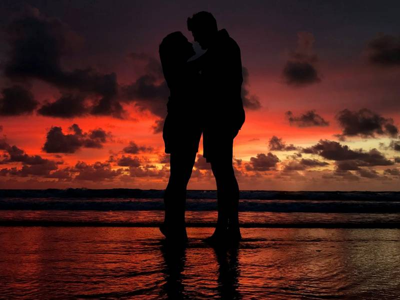 Silhouette of a couple embracing on a beach at sunset
