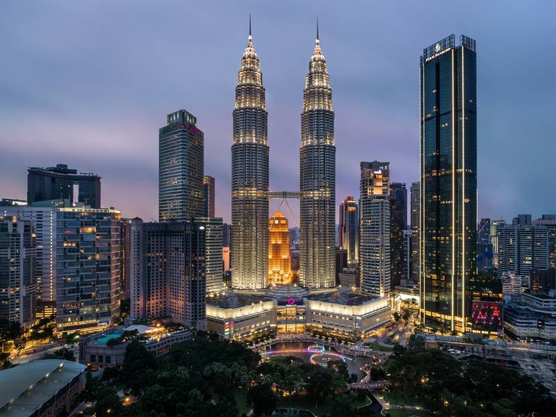Petronas Twin Towers lit up at dusk in Kuala Lumpur