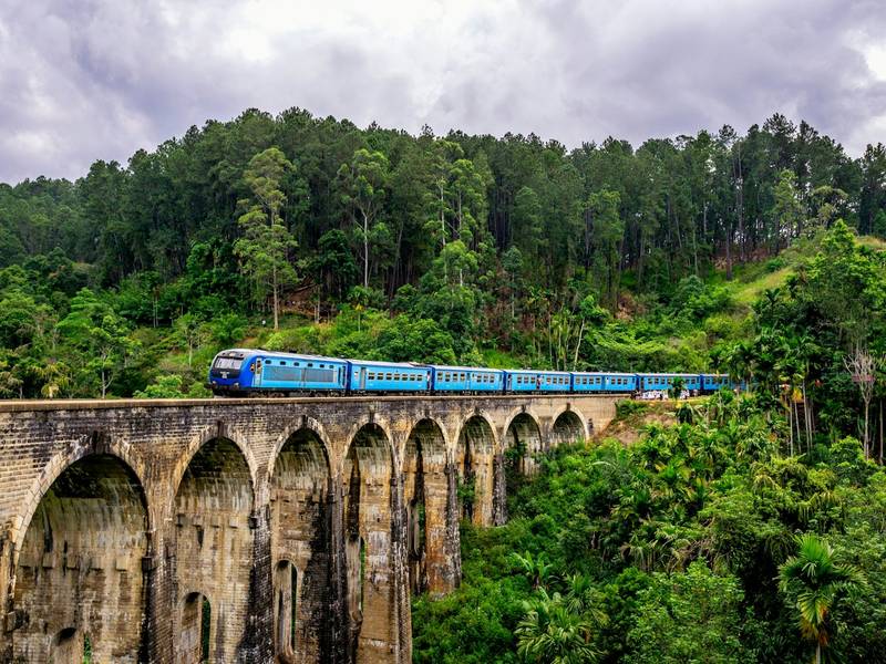 Blue train crossing the Nine Arches Bridge in Ella, Sri Lanka