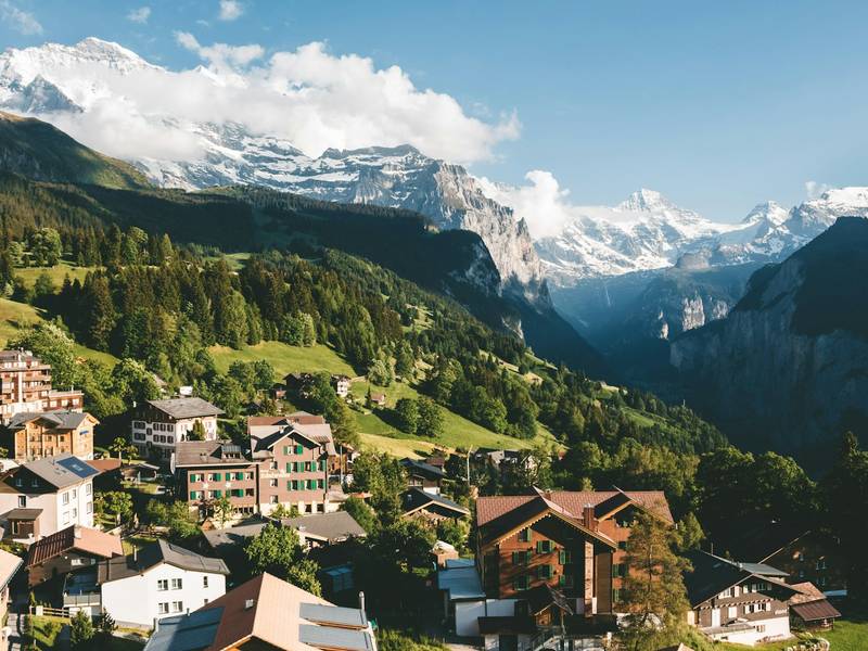 Swiss house beside a lake below mountains